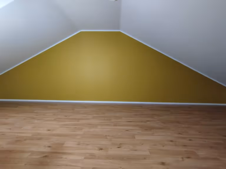 Huoneessa on vihreä seinä, valkoinen katto ja puulattia.