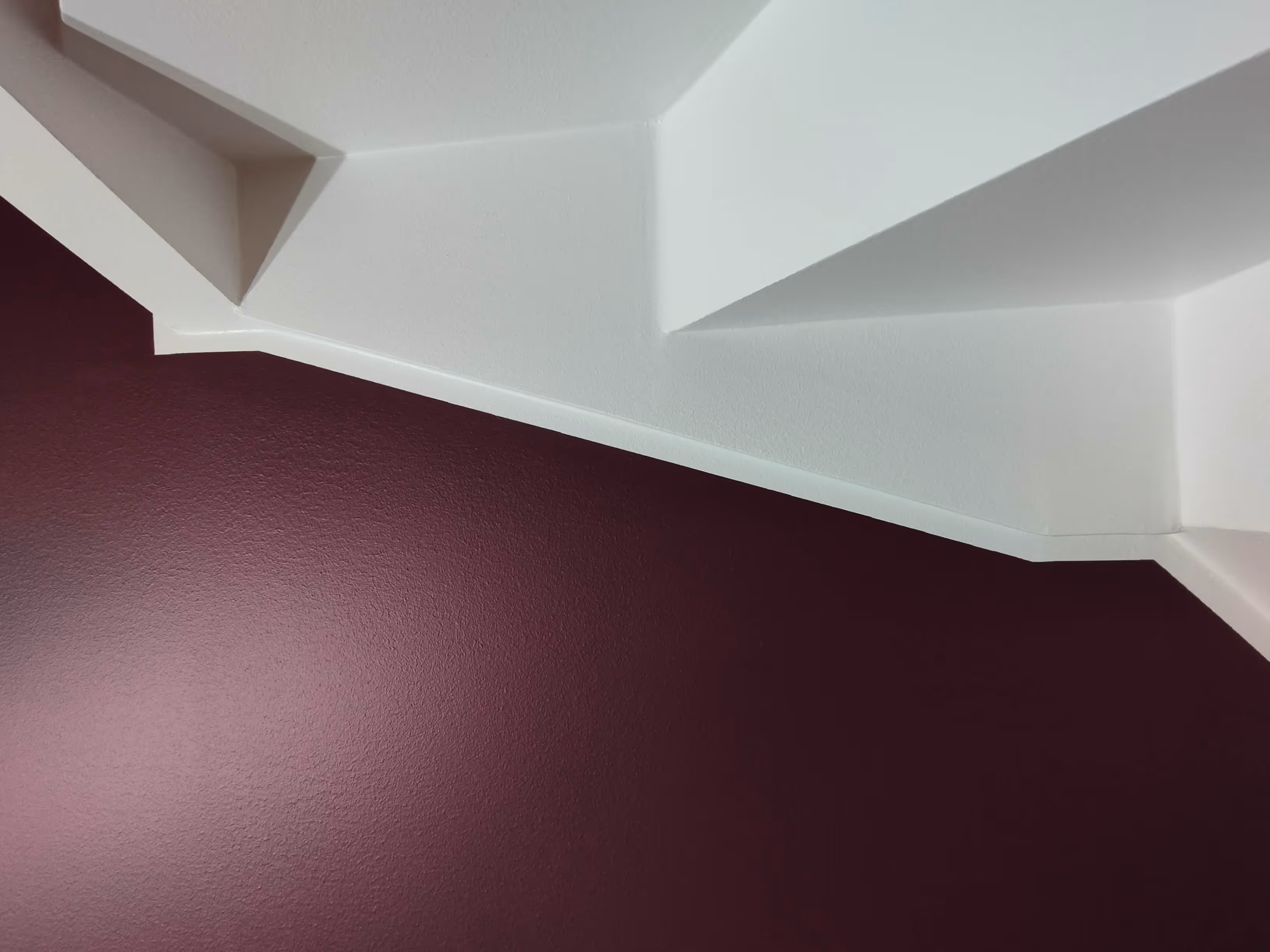 Valkoinen katto ja viininpunainen seinä, epätavallinen arkkitehtuuri ja valaistus.